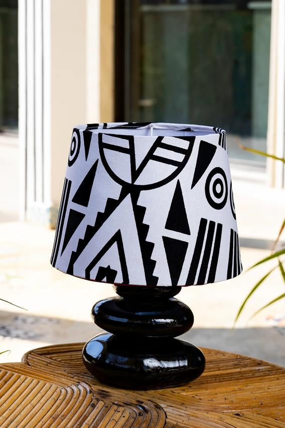 Black and white patterned lampshade on a wooden surface with a blurred background