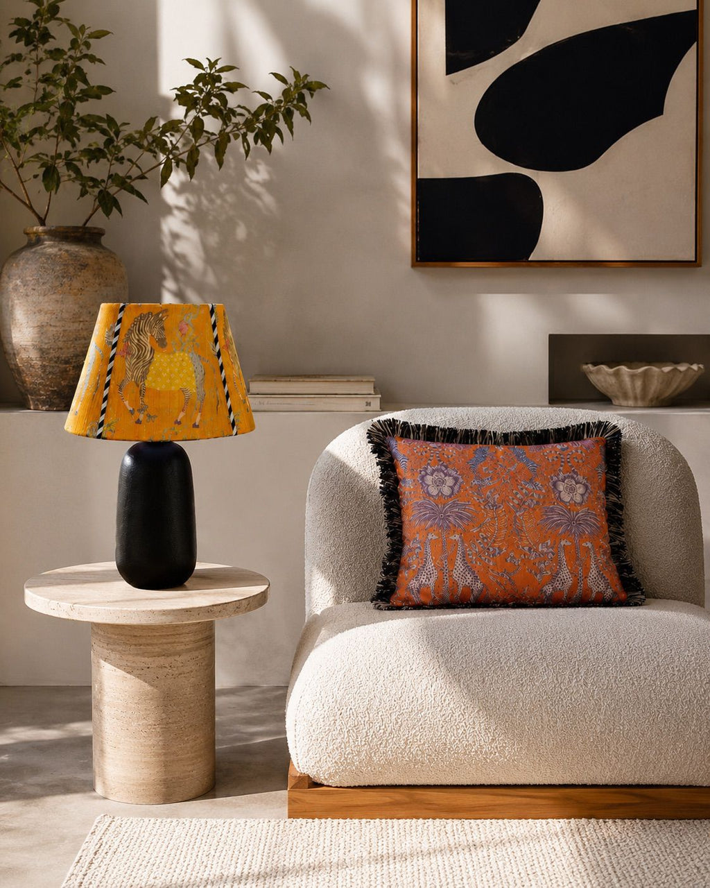 Living room with a white armchair, decorative pillow, side table with lamp, and abstract art on the wall.
