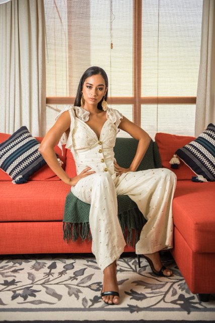 Woman in a white outfit sitting on a red couch in a stylish room.