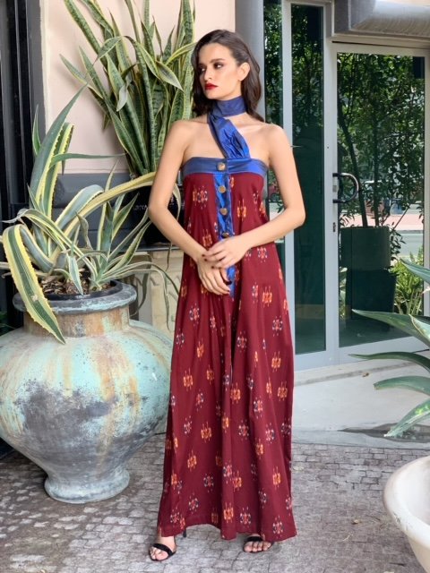 Woman in a red and blue dress standing outdoors with plants in the background