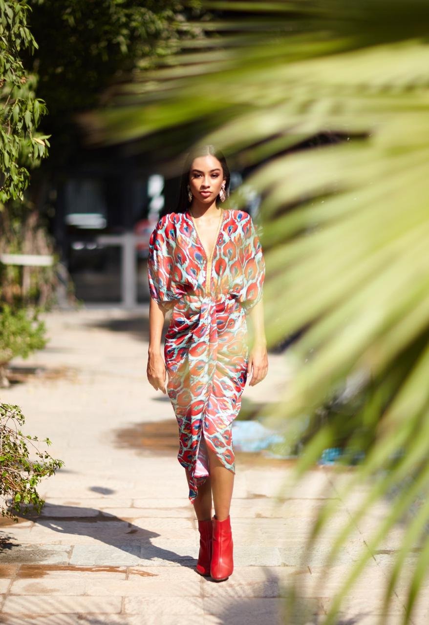 Woman in a colorful dress walking outdoors with palm leaves in the foreground