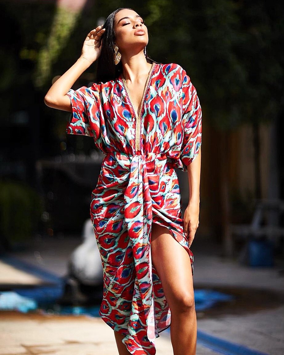 Woman wearing a colorful patterned dress standing outdoors.
