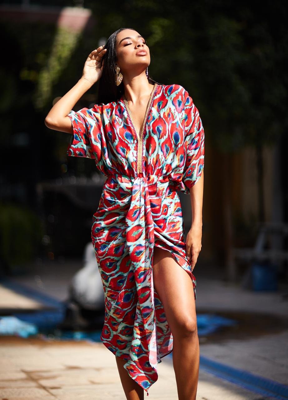 Woman wearing a colorful patterned dress standing outdoors.