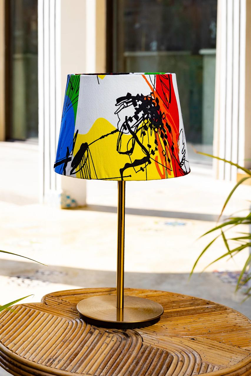 Table lamp with a colorful abstract shade on a wooden table.