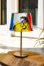 Table lamp with a colorful abstract shade on a wooden table.