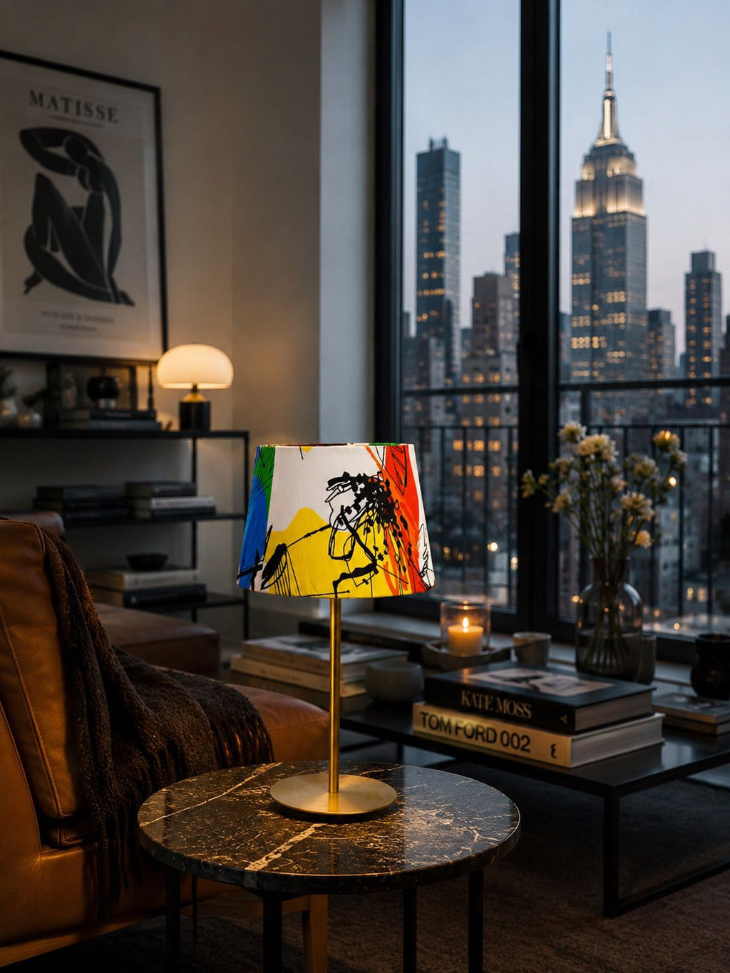 Modern living room with a colorful lamp, books, and a cityscape view.